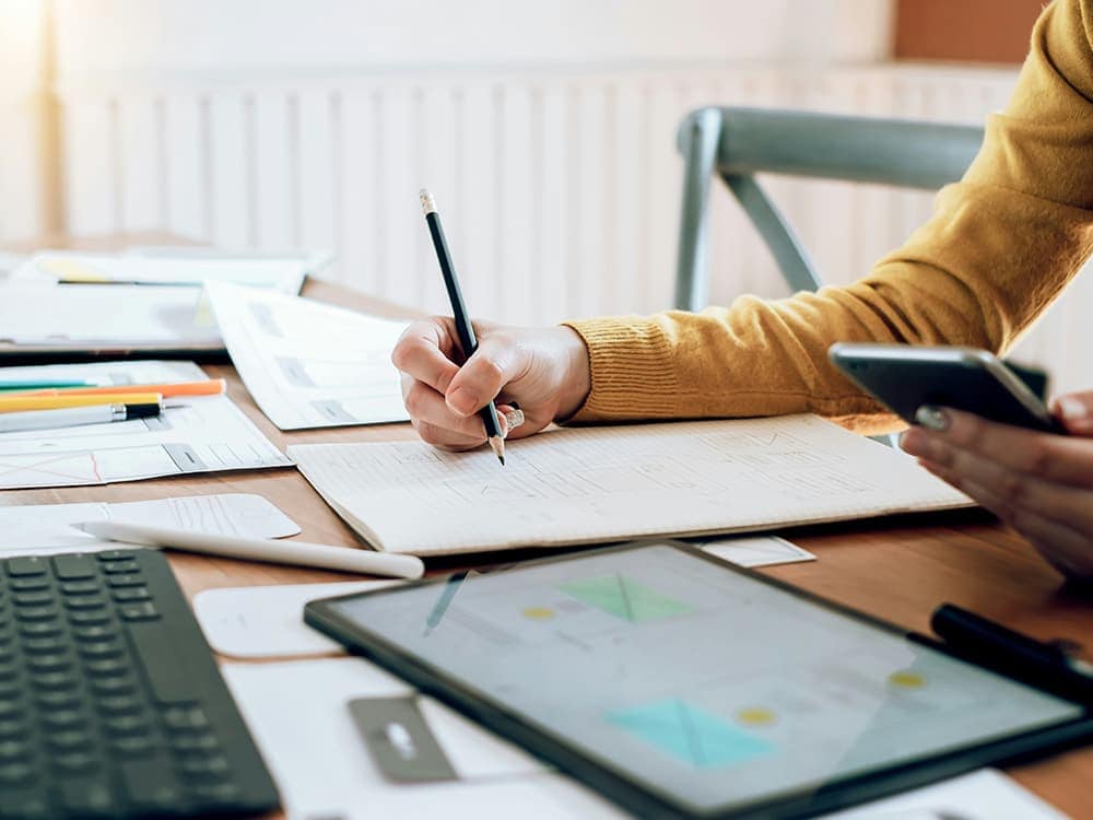 Person working with documents and digital devices at a desk.