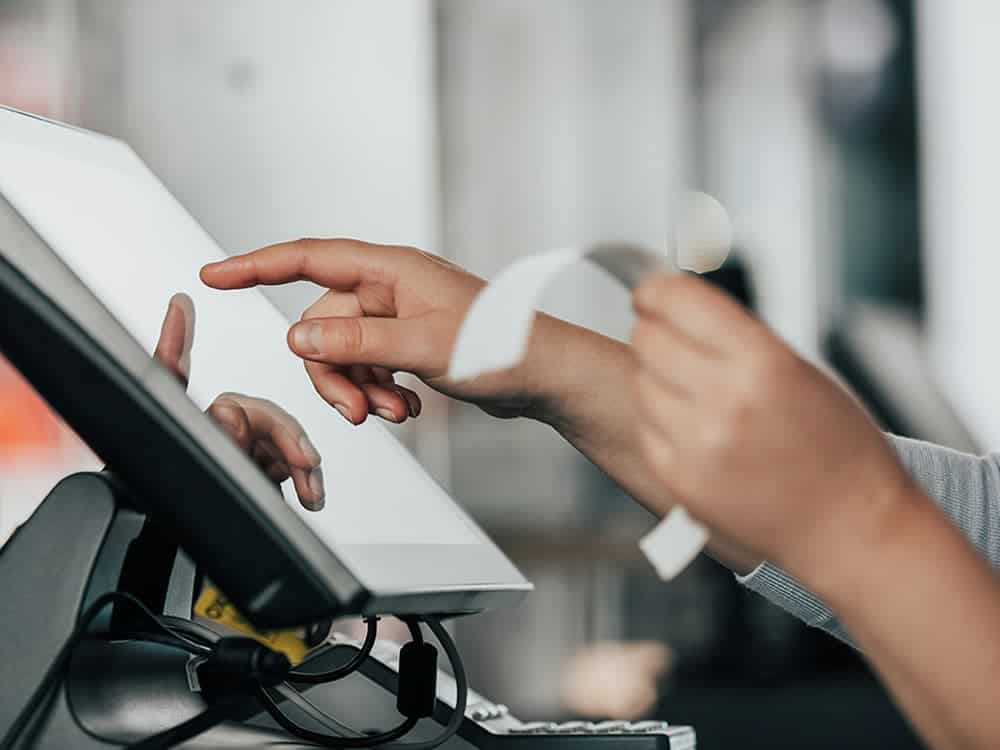 Person using a payment terminal touchscreen for transactions.