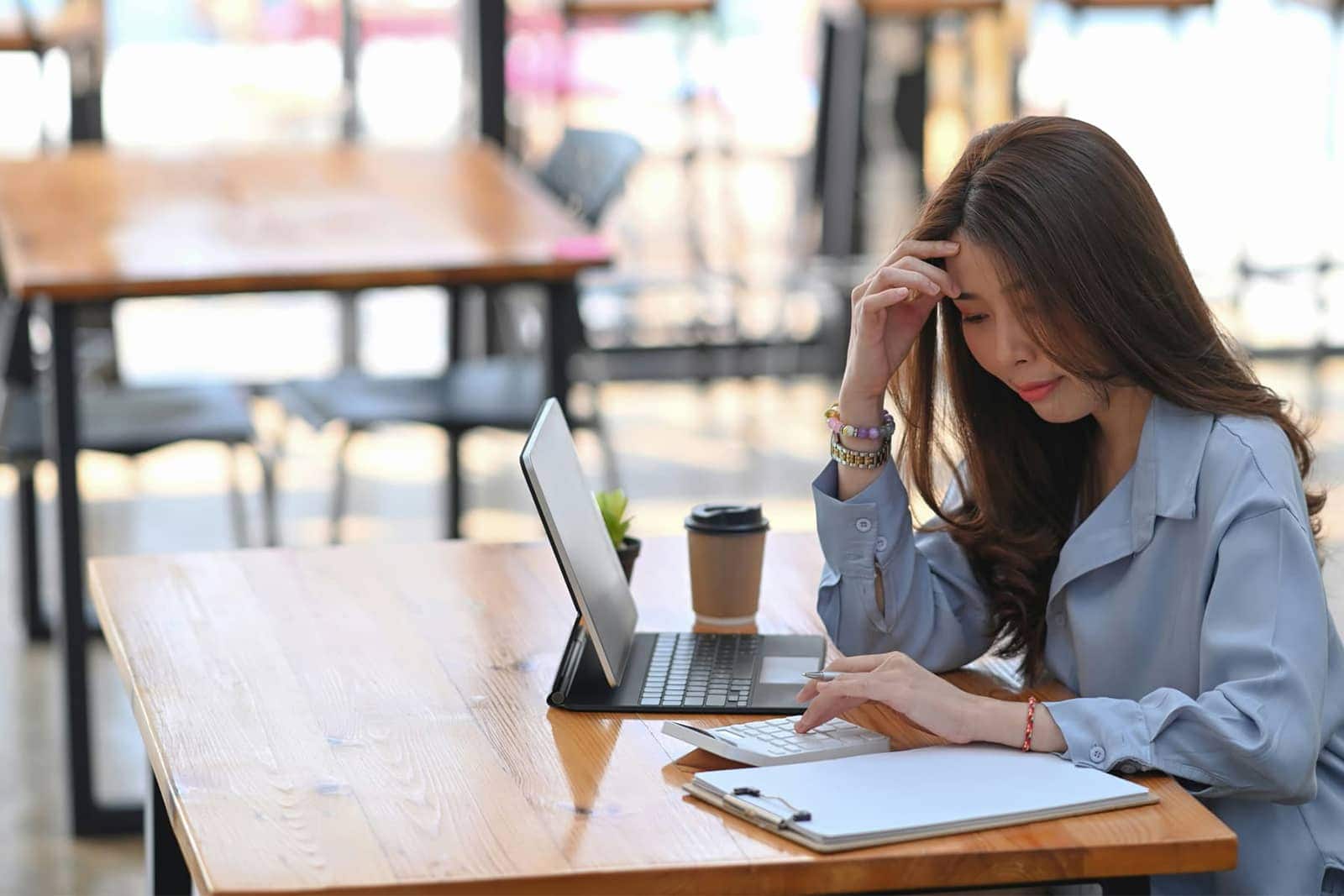 Stressful woman working on laptop in a cafe, experiencing frustration or fatigue while working or st.